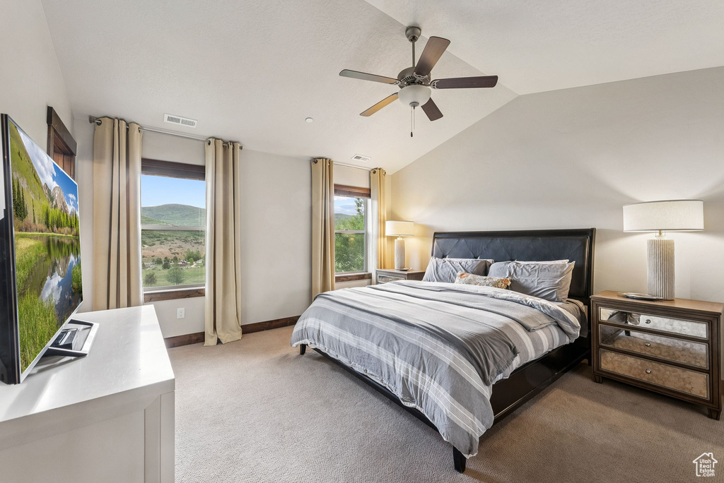 Bedroom with lofted ceiling, light carpet, multiple windows, and ceiling fan