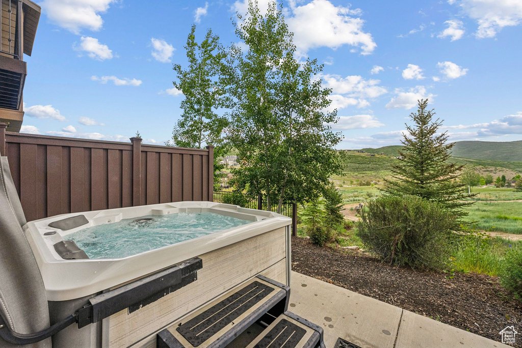 View of patio / terrace with a hot tub and a mountain view