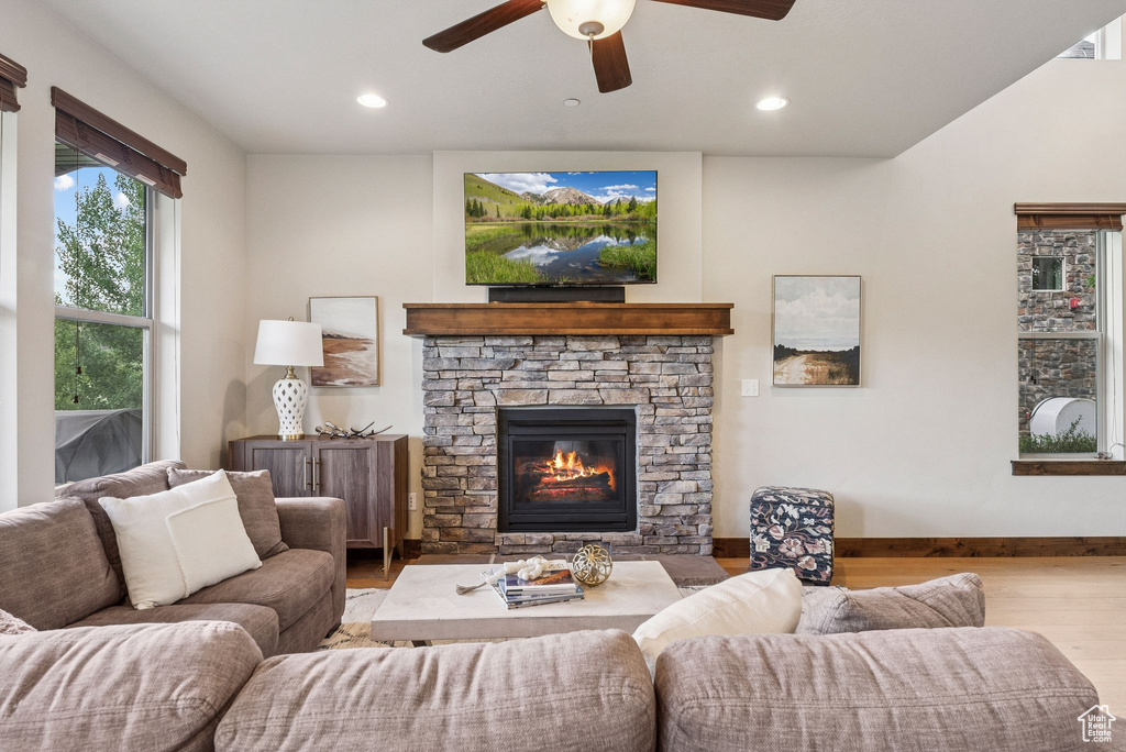 Living room featuring wood finished floors, a ceiling fan, a stone fireplace, and recessed lighting