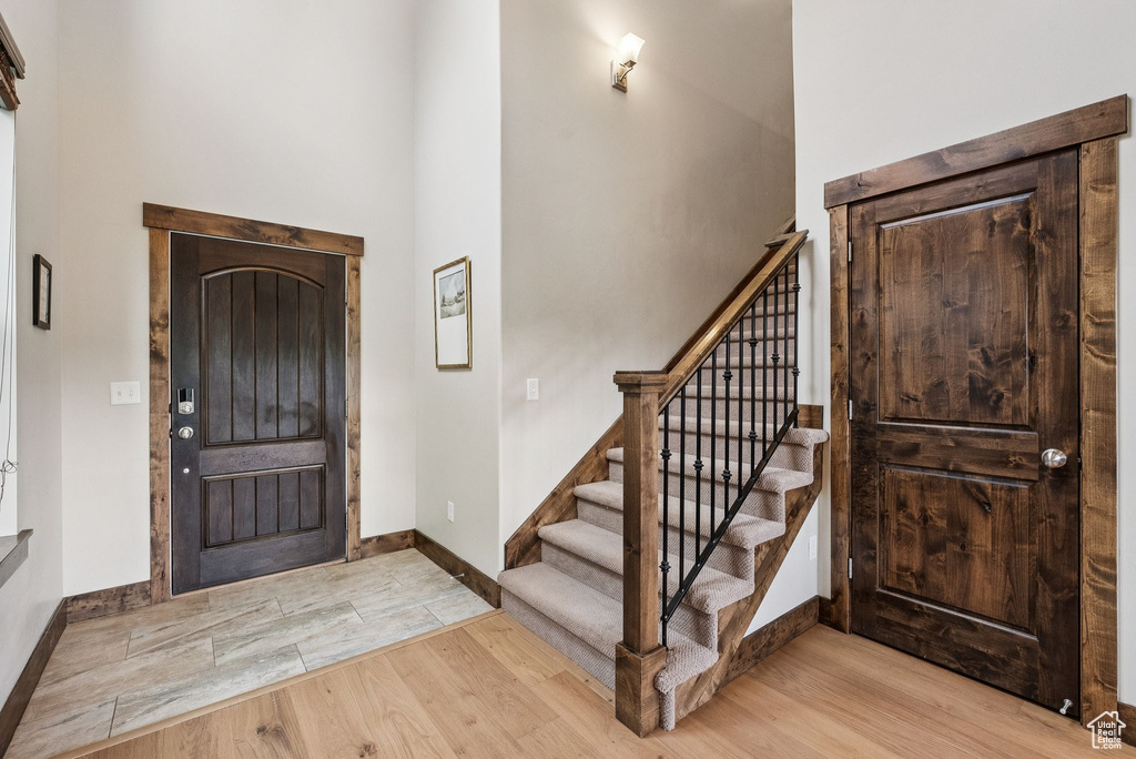 Entryway featuring light wood-style floors, stairway, and a towering ceiling