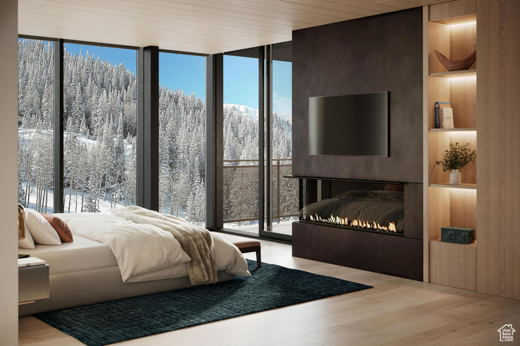 Bedroom featuring a wall of windows, a warm lit fireplace, wood finished floors, and multiple windows