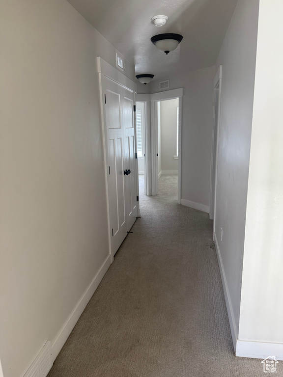 Hall featuring light colored carpet and baseboards