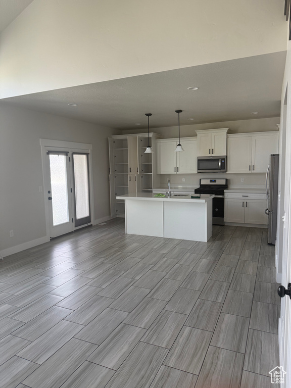 Kitchen with appliances with stainless steel finishes, open floor plan, white cabinetry, wood finish floors, and recessed lighting