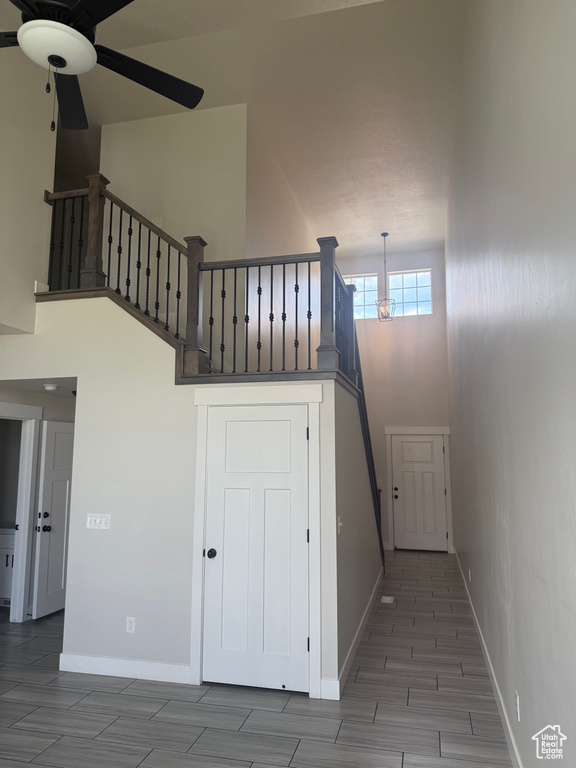 Staircase with a ceiling fan, a towering ceiling, and wood finish floors