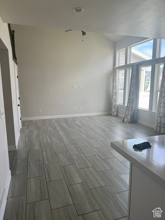 Unfurnished living room featuring baseboards and a textured ceiling