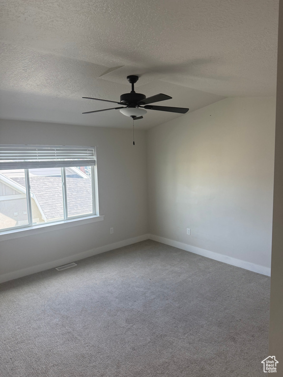 Unfurnished room featuring a textured ceiling, a ceiling fan, and carpet
