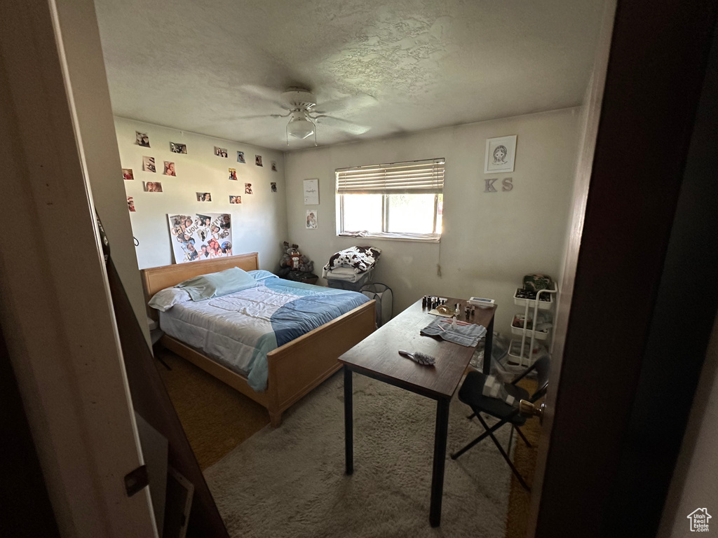 Bedroom with carpet, a textured ceiling, and a ceiling fan