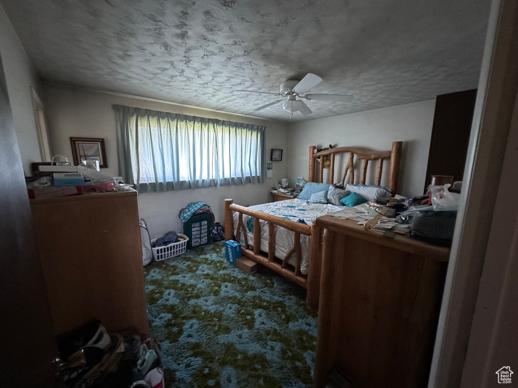 Carpeted bedroom featuring a textured ceiling and a ceiling fan