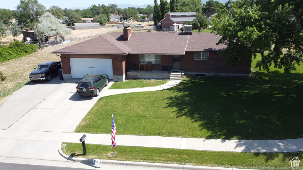 Ranch-style home with covered porch, concrete driveway, a garage, brick siding, and a chimney