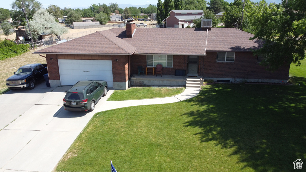 Ranch-style house with driveway, a garage, brick siding, roof with shingles, and a front lawn