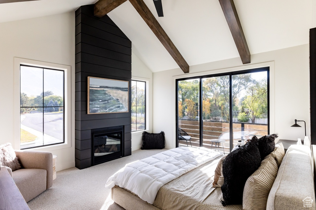 Carpeted bedroom featuring access to exterior, beam ceiling, a large fireplace, and high vaulted ceiling