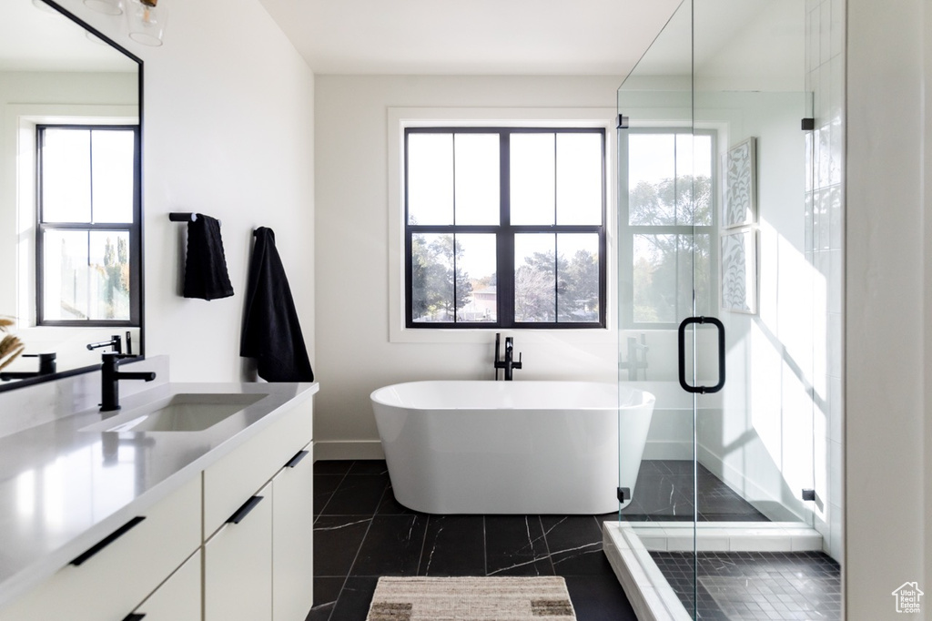 Full bathroom with vanity, a freestanding bath, a shower stall, and tile patterned flooring
