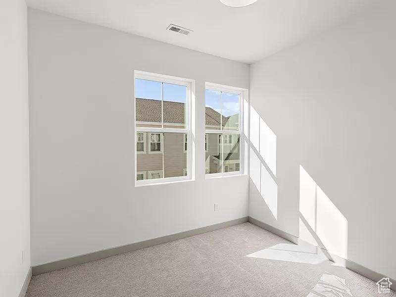 Empty room featuring baseboards and light colored carpet