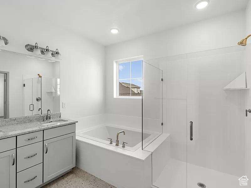 Bathroom featuring a stall shower, vanity, a garden tub, speckle patterned floor, and recessed lighting