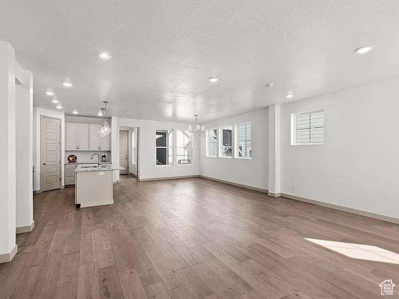 Unfurnished living room with a chandelier, recessed lighting, dark wood-style floors, and a textured ceiling