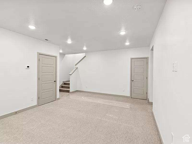 Below grade area with recessed lighting, stairway, and light carpet
