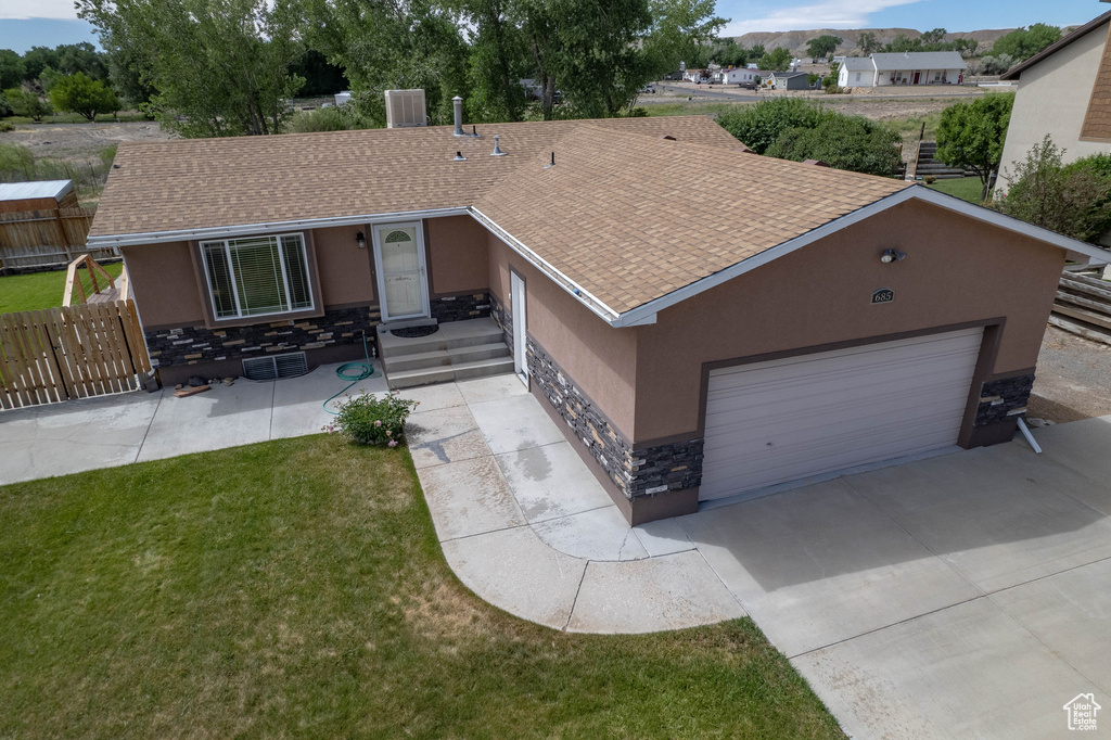 Single story home featuring stone siding, stucco siding, a shingled roof, an attached garage, and concrete driveway