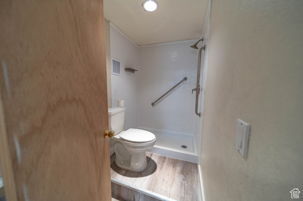 Full bath with a stall shower, wood finished floors, and crown molding