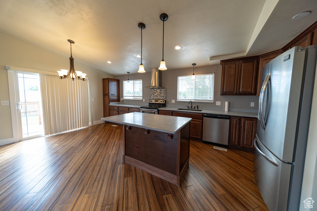 Kitchen with stainless steel appliances, a center island, a chandelier, dark wood-style flooring, and decorative light fixtures
