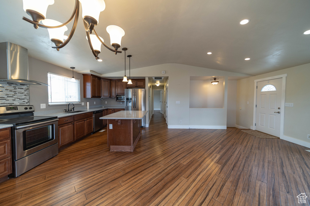 Kitchen with appliances with stainless steel finishes, extractor fan, vaulted ceiling, dark wood-style flooring, and tasteful backsplash