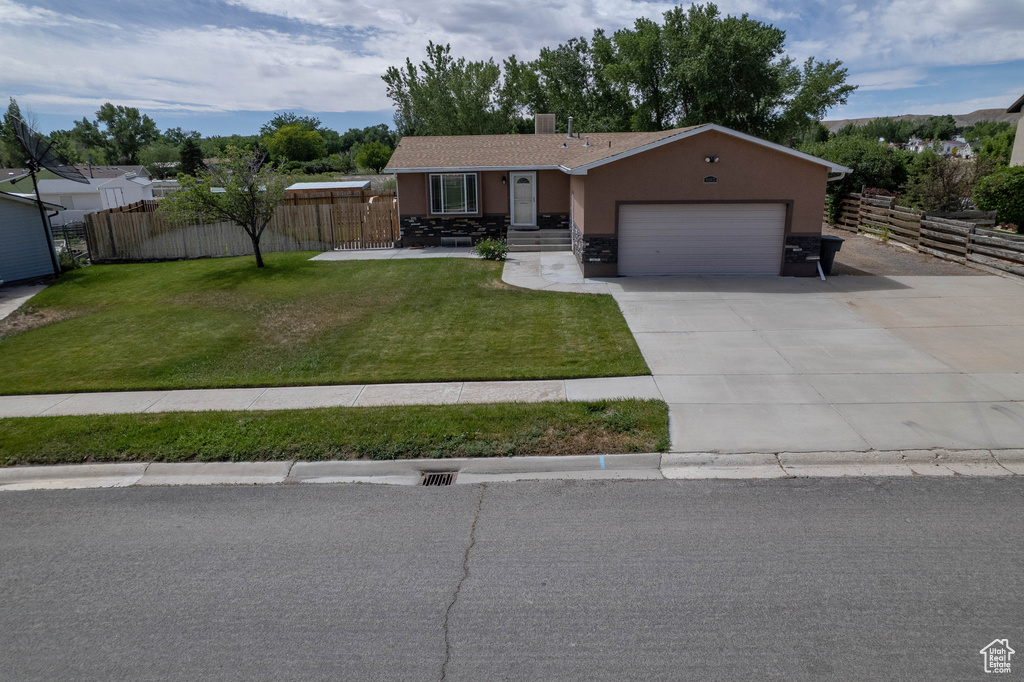 Single story home featuring stucco siding, an attached garage, driveway, and stone siding