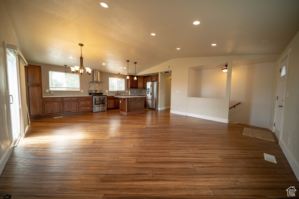 Unfurnished living room featuring lofted ceiling, a chandelier, dark wood finished floors, and recessed lighting