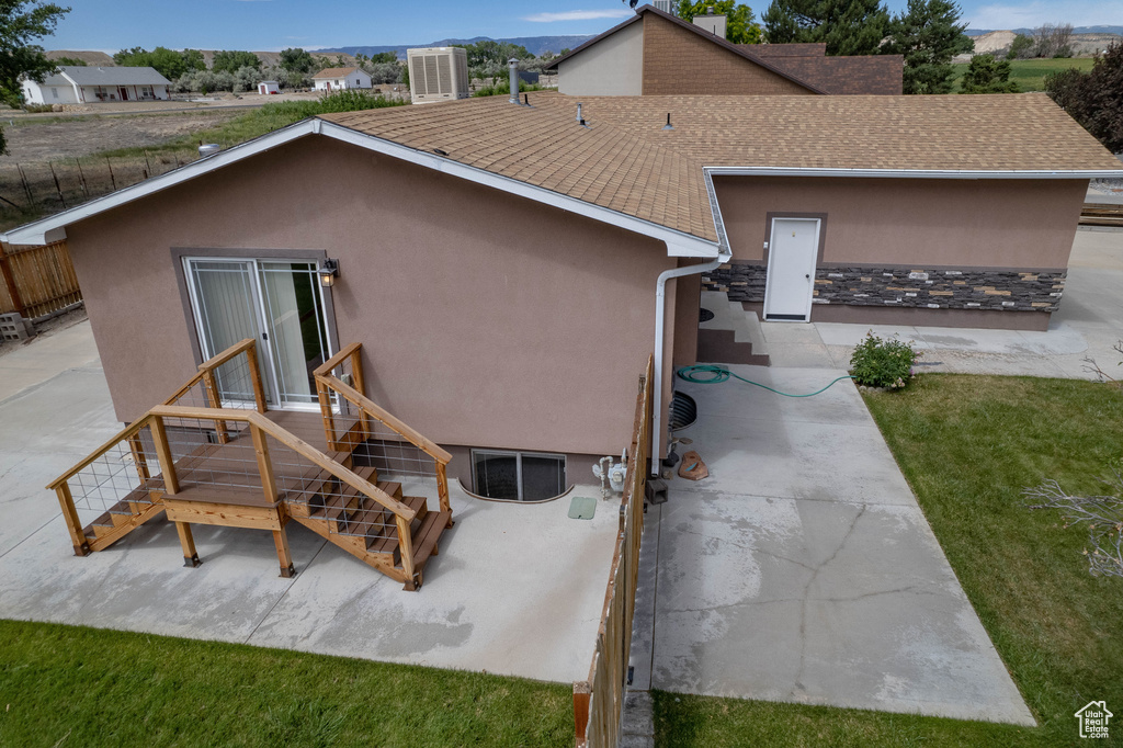 Back of property featuring roof with shingles, stucco siding, and entry steps