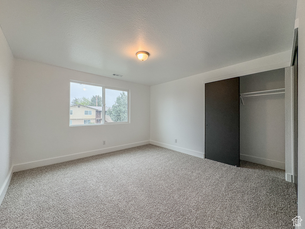 Unfurnished bedroom with a closet, carpet, and a textured ceiling