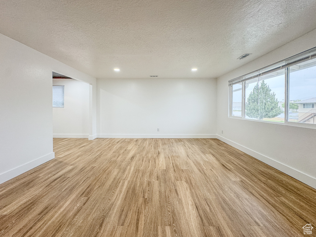 Unfurnished room featuring light wood-style floors, a textured ceiling, and recessed lighting