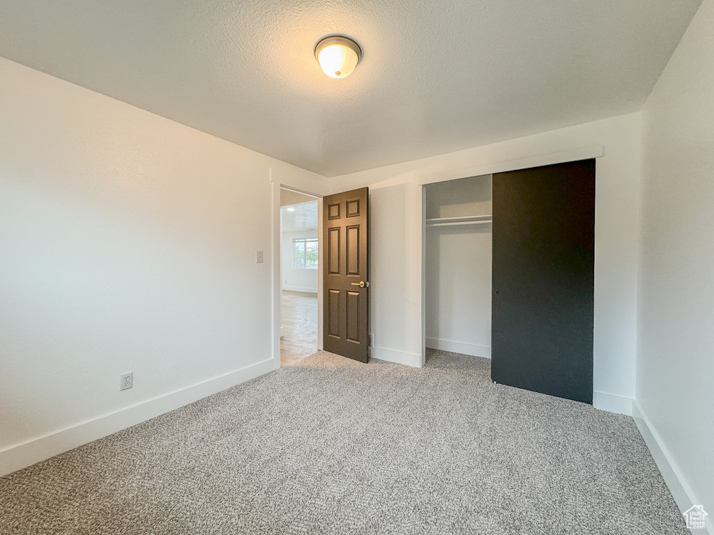 Unfurnished bedroom with light colored carpet and a closet