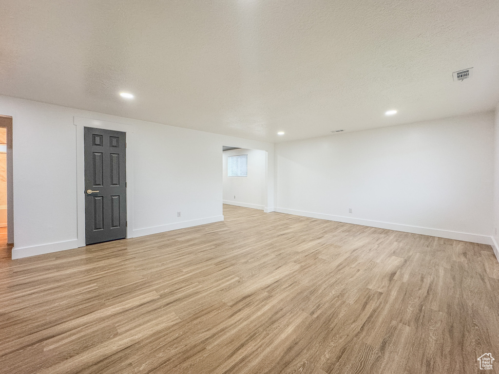 Basement featuring light wood-style flooring, recessed lighting, and a textured ceiling