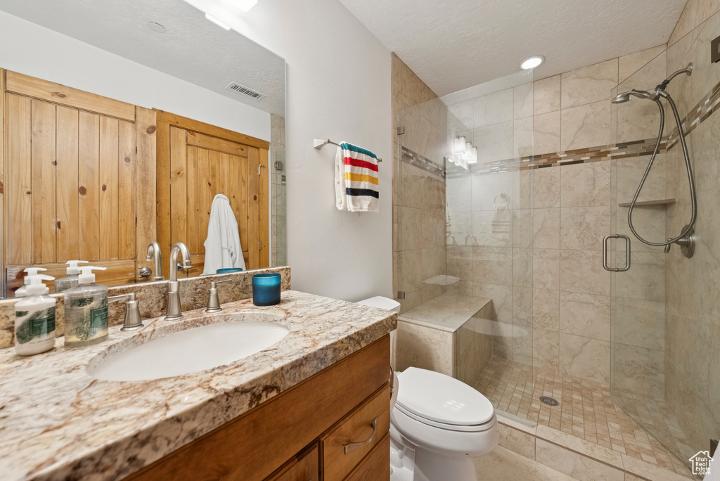 Full bathroom with a shower stall, vanity, and a textured ceiling
