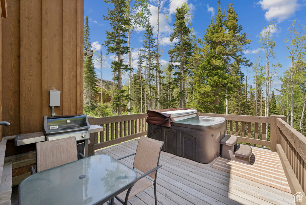 Wooden deck with area for grilling, outdoor dining area, and a hot tub