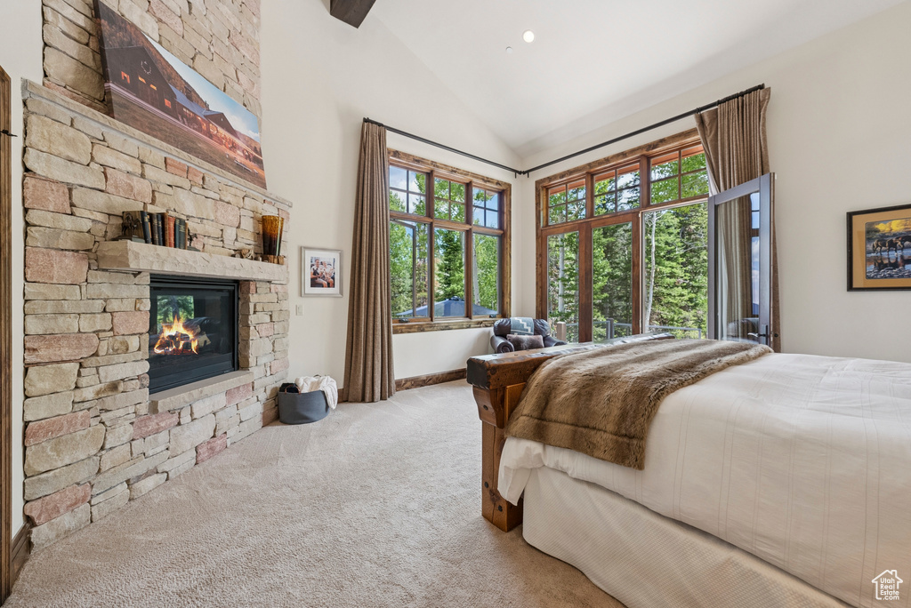 Bedroom featuring a stone fireplace, carpet, and high vaulted ceiling