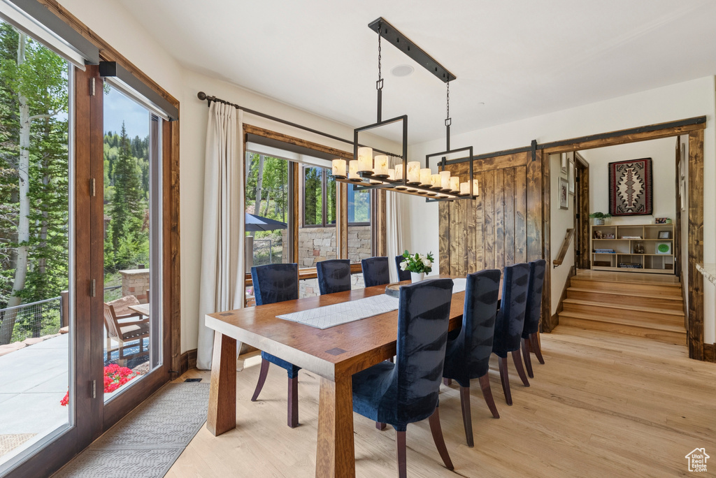 Dining space featuring light wood-style floors, a chandelier, and a barn door