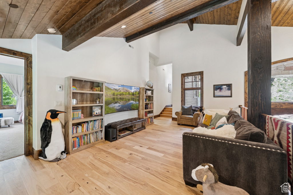 Living room featuring hardwood / wood-style flooring, plenty of natural light, a wooden ceiling with exposed beams, and high vaulted ceiling