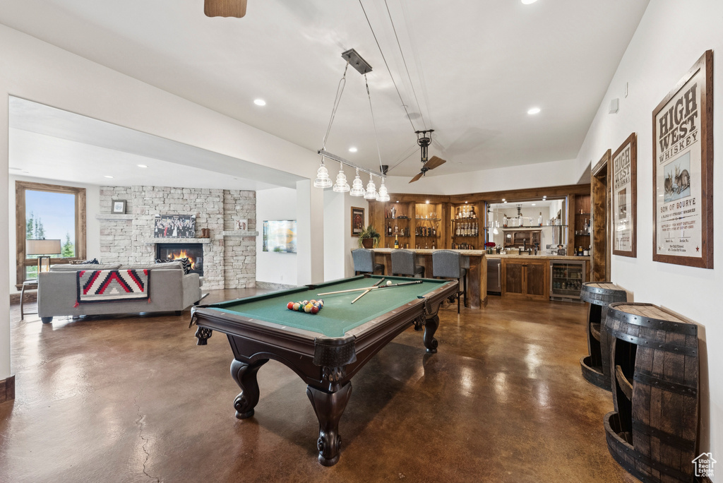 Recreation room featuring concrete floors, billiards, bar, wine cooler, and a fireplace