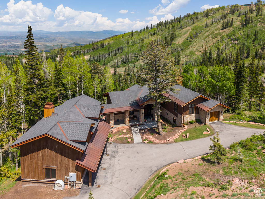 Aerial view of property and surrounding area with a mountainous background and a heavily wooded area