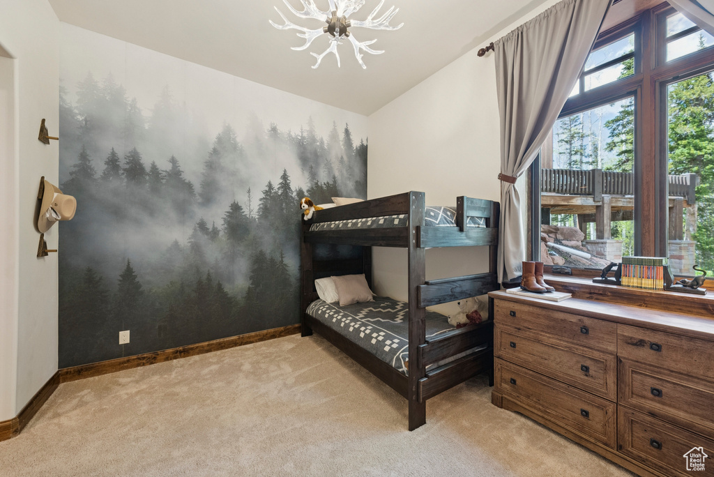 Bedroom featuring a chandelier, light carpet, and vaulted ceiling