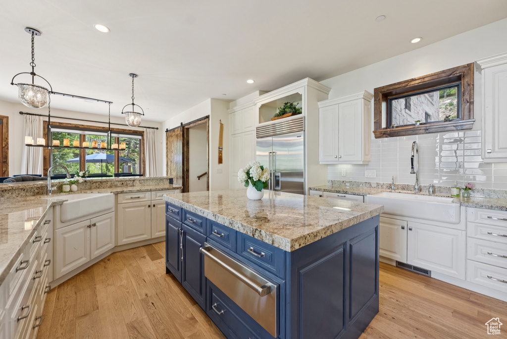 Kitchen featuring blue cabinetry, stainless steel built in fridge, a warming drawer, white cabinets, and a kitchen island