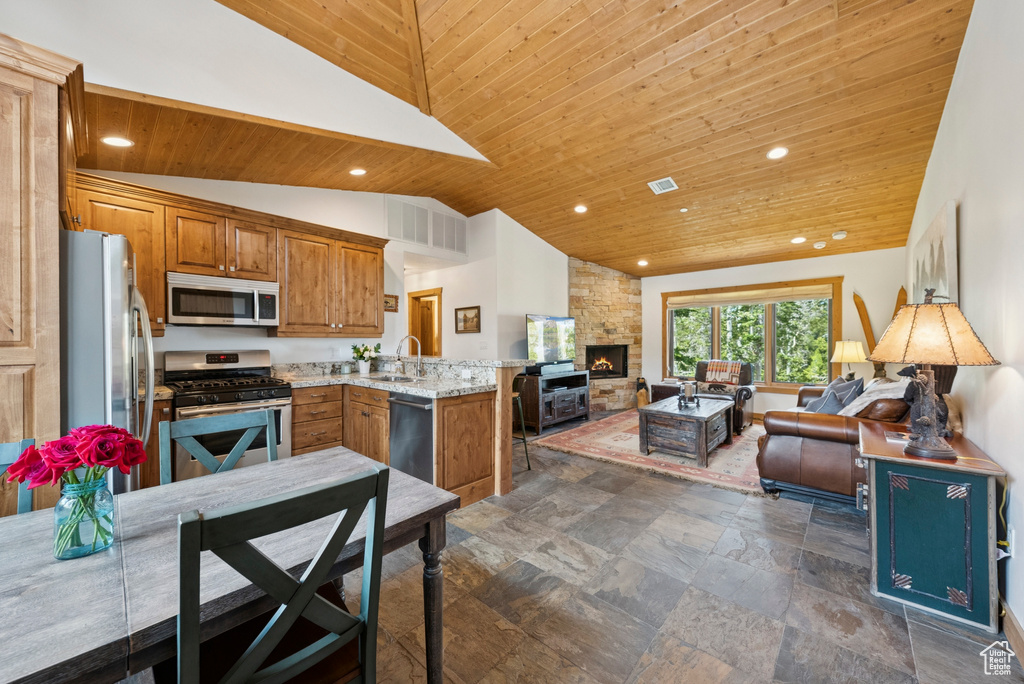 Kitchen with appliances with stainless steel finishes, open floor plan, vaulted ceiling, wood ceiling, and a peninsula