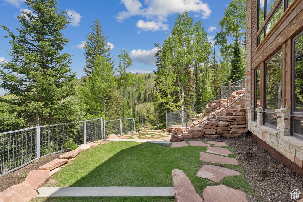 View of yard with stairs and a view of trees
