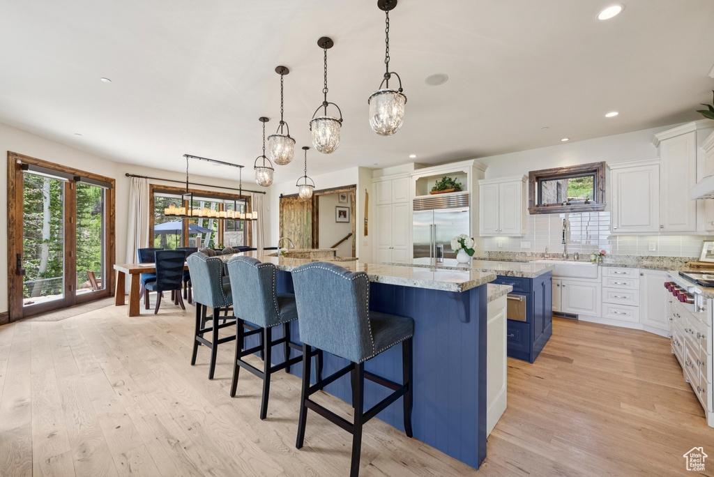 Kitchen with stainless steel appliances, a large island, white cabinetry, and recessed lighting