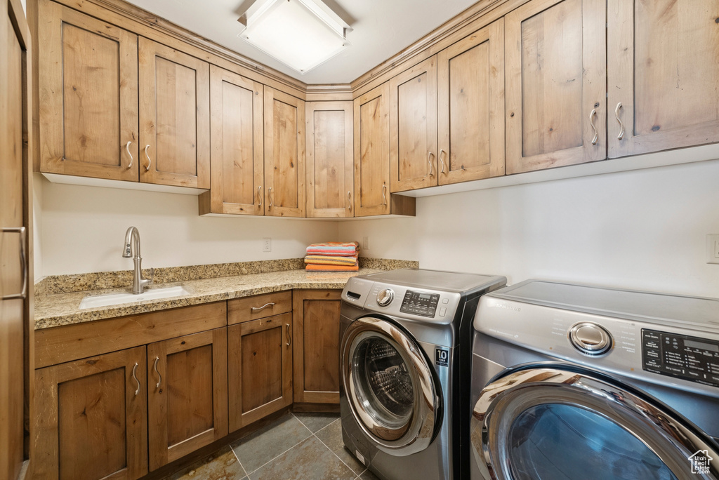 Laundry area featuring separate washer and dryer, cabinet space, and dark tile patterned flooring