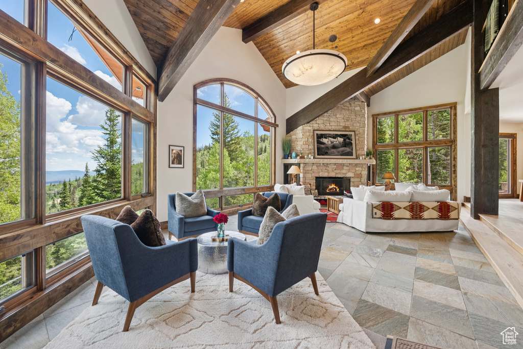 Living room featuring a wooden ceiling with exposed beams, high vaulted ceiling, a stone fireplace, and recessed lighting