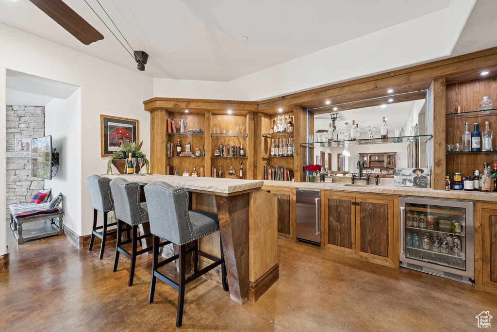 Indoor wet bar featuring beverage cooler and finished concrete flooring