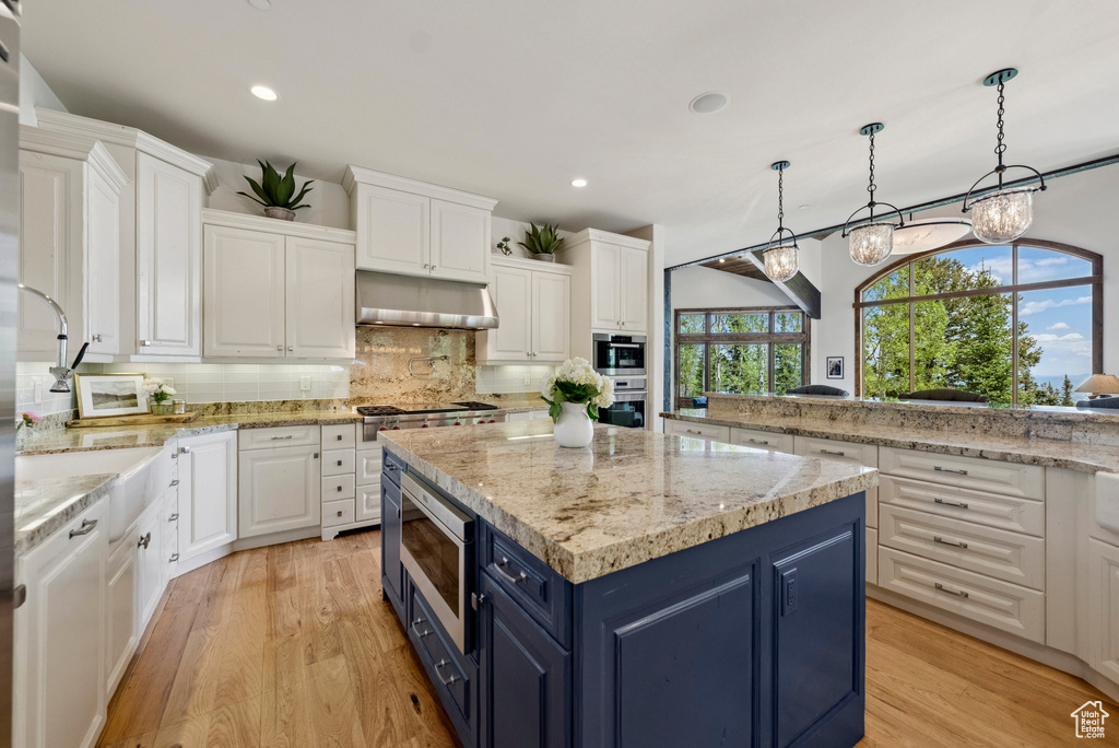 Kitchen with blue cabinets, stainless steel appliances, white cabinets, a center island, and recessed lighting