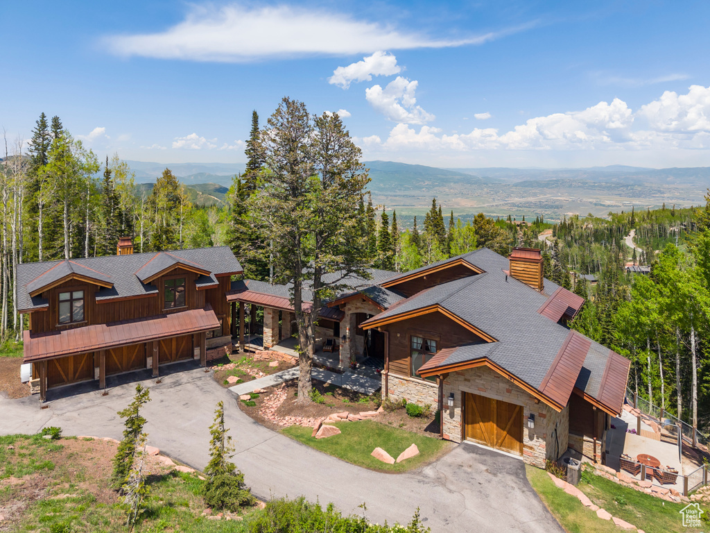 View of front of property featuring a chimney, stone siding, a garage, and a mountain view
