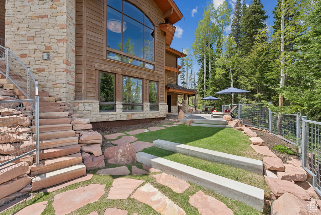 Back of property with stone siding, stairs, and a patio