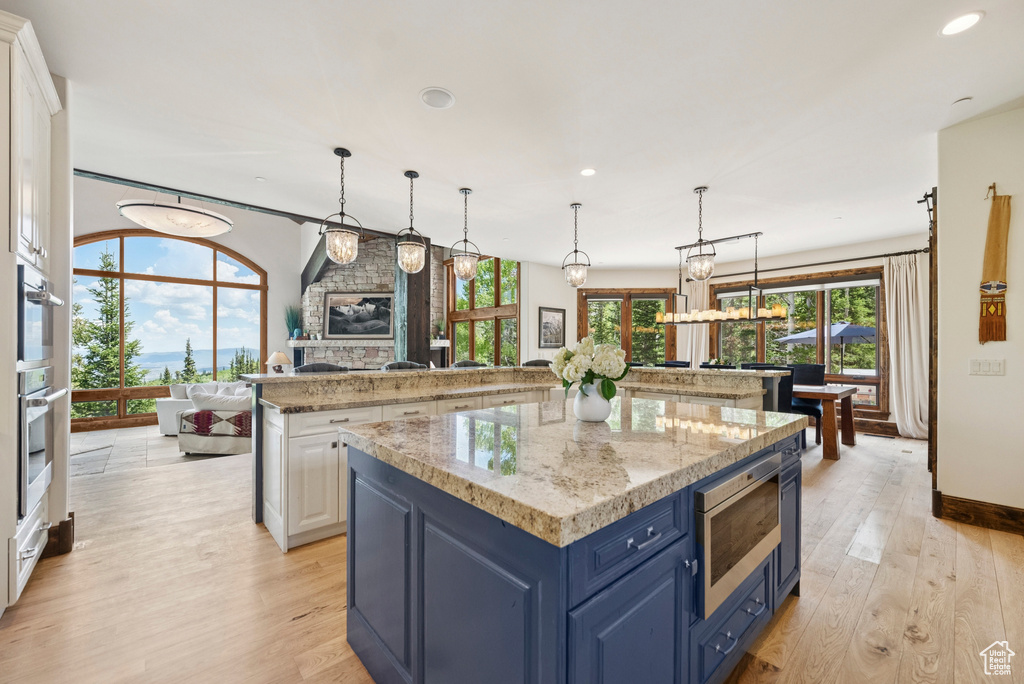Kitchen featuring stainless steel appliances, a spacious island, blue cabinetry, light wood-type flooring, and recessed lighting